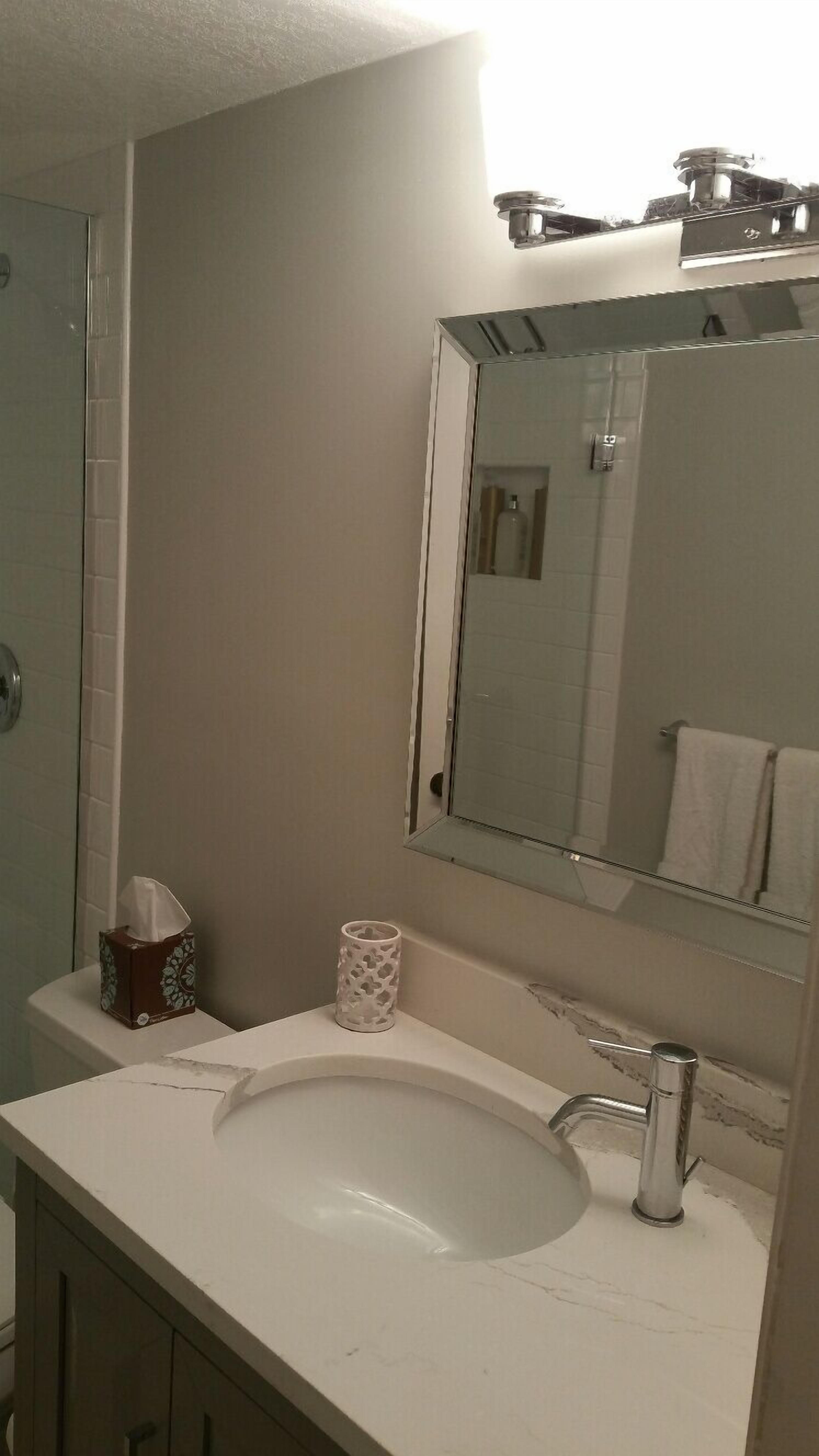 Un baño con un lavabo blanco, un espejo y un perchero para toallas.