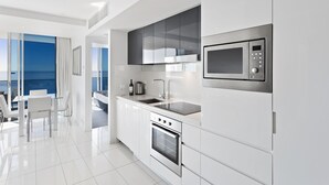A modern kitchen with a built-in oven, microwave, and a large window overlooking the sea. - H Residences Ocean View (Surfers Paradise)