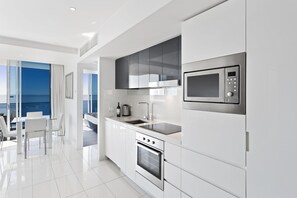 A modern kitchen with a built-in oven, microwave, and a large window overlooking the sea. - H Residences Ocean View (Surfers Paradise)