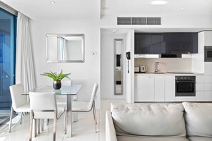 Uma sala de estar moderna com uma mesa de jantar de vidro, cadeiras brancas e um sofá de couro.