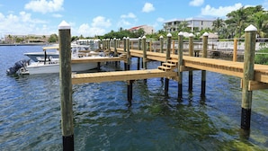 A wooden dock extending into calm water with boats moored at the end.