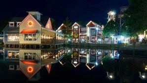 Un hotel frente al agua con varias edificaciones, incluyendo un restaurante y un bar, reflejado en el agua.