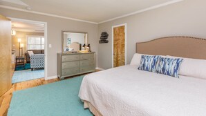A bedroom with a large bed, a dresser, a mirror, and a door leading to another room. - Spacious 1BR w/ KING Bed Near Hospital & Downtown (Winston-Salem)