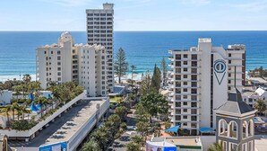 A coastal hotel with multiple high-rise buildings, a beach view, and a prominent logo on one building. - Chevron Renaissance Ocean View (Surfers Paradise)
