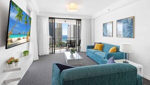 A modern hotel room with a large balcony, a sofa, a coffee table, and a TV mounted on the wall. - Chevron Renaissance Ocean View (Surfers Paradise)