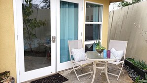 A patio with two white chairs, a small table, and a potted plant.