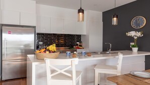 Una cocina moderna con una isla central, electrodomésticos de acero inoxidable y un salpicadero negro.