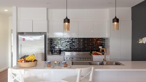 Una cocina moderna con un refrigerador de acero inoxidable, una estufa a gas y lámparas colgantes.