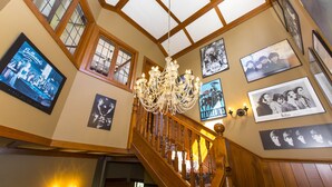 Eine prachtvolle Treppe mit Holzwangen und einem Chandelier, umgeben von gerahmten Memorabilien der Beatles an den Wänden.