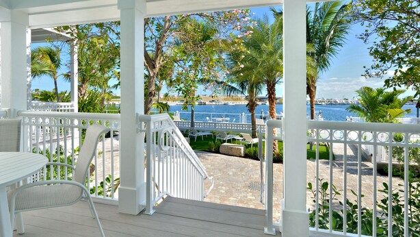 A covered outdoor area with a white railing, a table, and chairs. - Waterfront 3-Bedroom Condo at Bayfront Suites & Marina- CLEANING FEE INCLUDED (Key West)
