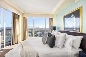 Habitación de hotel con una cama grande, vista a la ciudad y un cuadro en la pared.