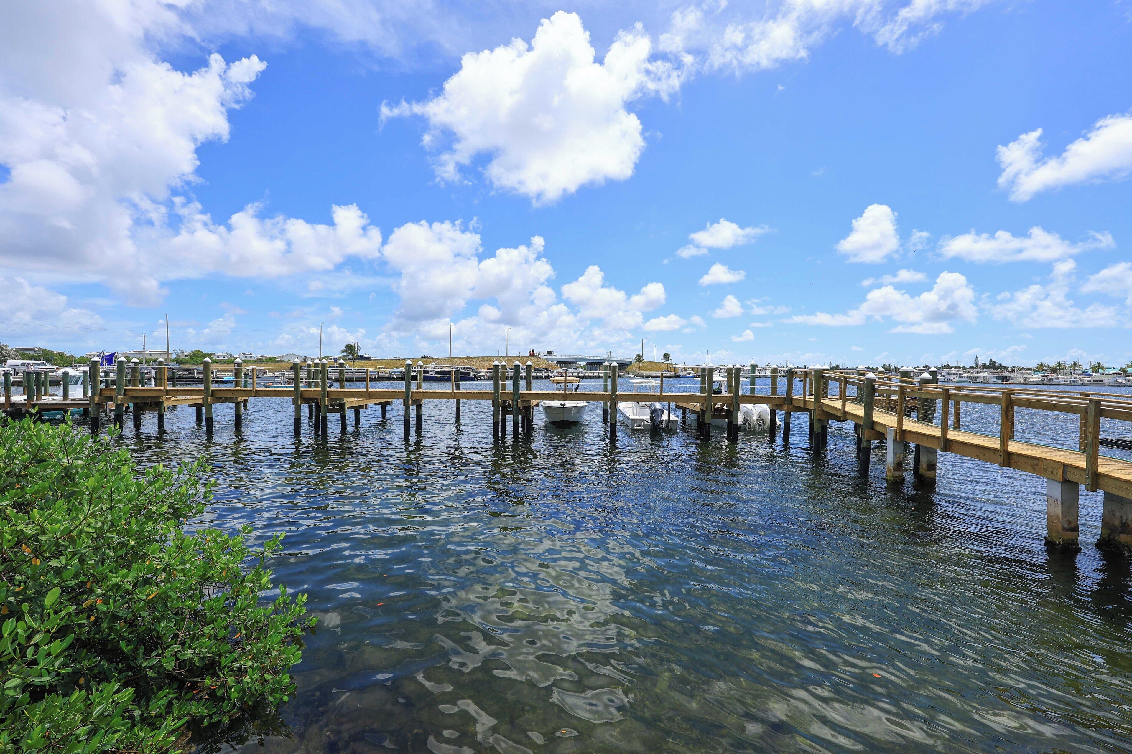 Un muelle de madera que se adentra en aguas tranquilas, con cielos despejados y algunas nubes dispersas.