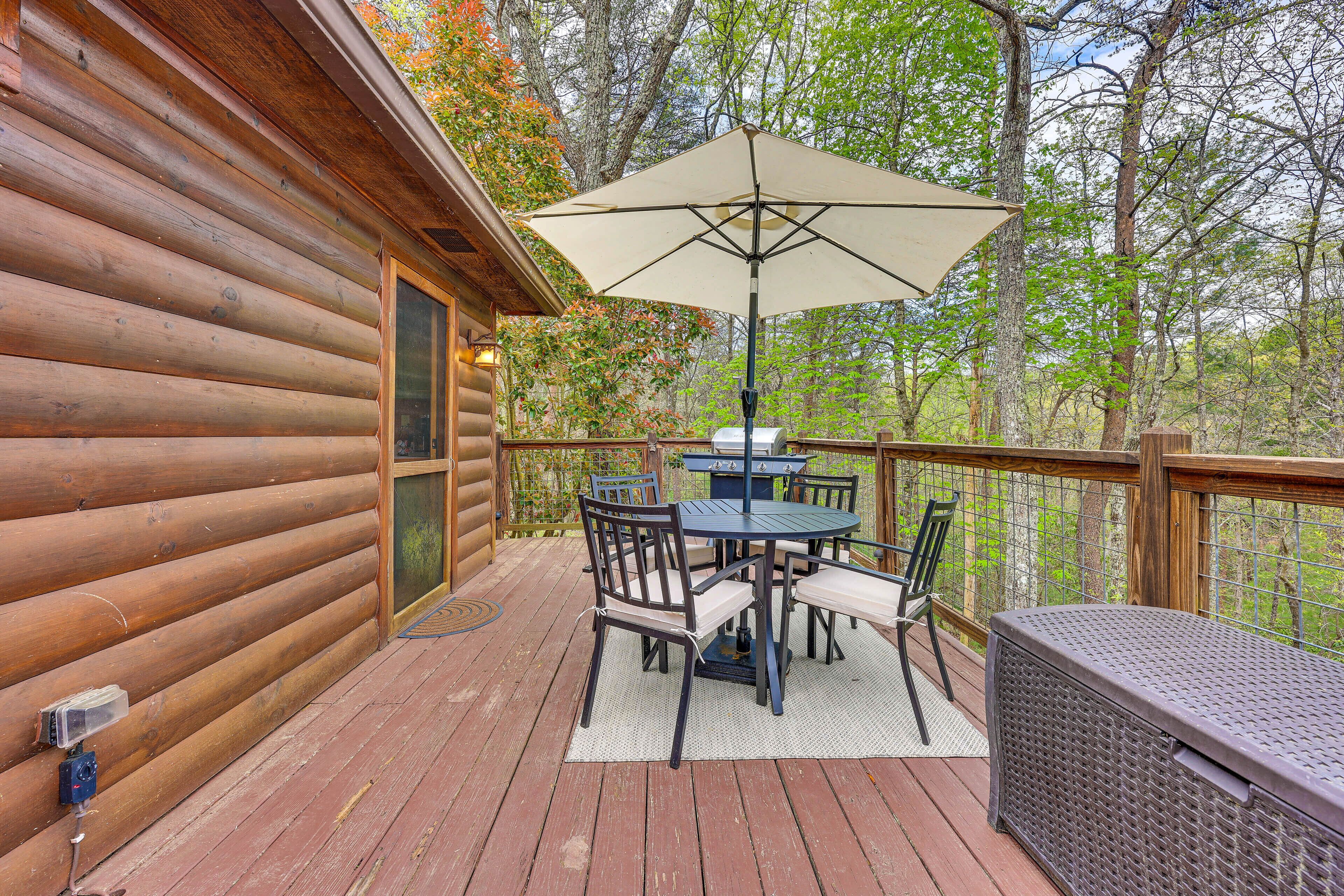 A wooden deck with a table and chairs, a grill, and a large umbrella.