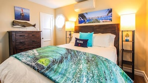 A hotel room with a bed, a dresser, a nightstand, a wall-mounted air conditioner, and two wall-mounted lamps. -  Steps to Beach and Bay with Garage Parking (compact car) & Air Conditioning! (Newport Beach)