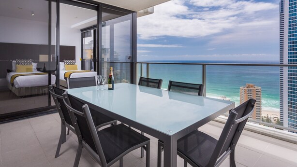 Ein modernes Hotelzimmer mit Balkon, das Blick auf den Ozean und die Stadt bietet.