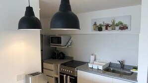 Una cocina moderna equipada con tostadora, hervidor, microondas, horno y lavabo.