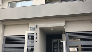 Un edificio moderno de varios pisos con fachada plana, numerado 355, que presenta una entrada central con una escalera metálica que conduce al interior.