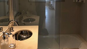 Un baño moderno con ducha de vidrio, lavamanos con espejo y un perchero para toallas.