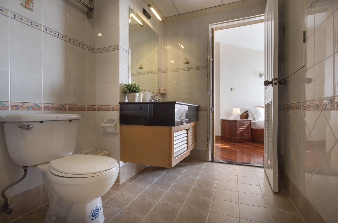 Un baño con inodoro, lavamanos con espejo y zona de ducha.