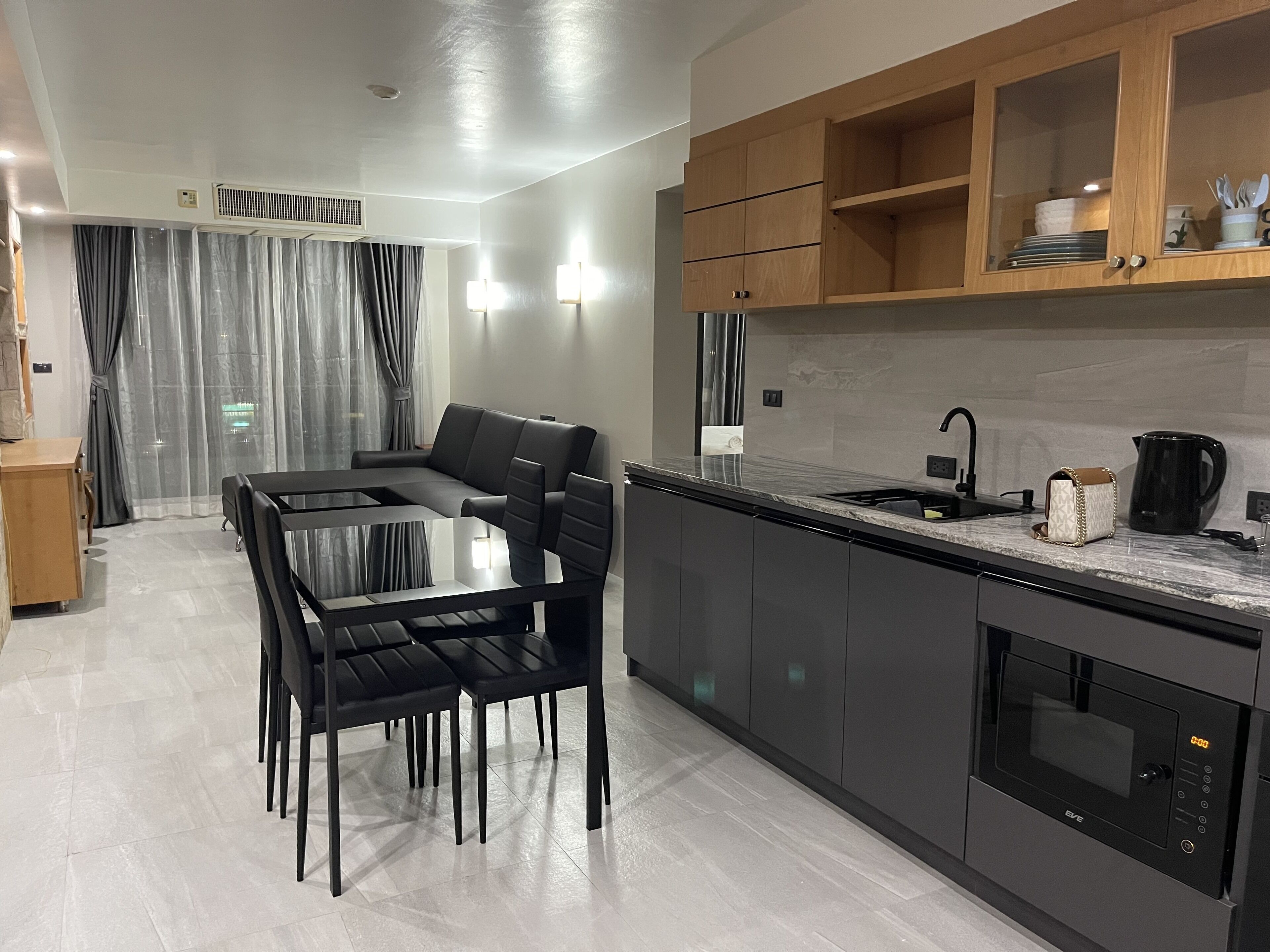 A modern kitchen with a dining area, featuring a built-in oven, a sink, and a coffee maker.