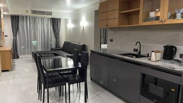 A modern kitchen with a dining area, featuring a built-in oven, a sink, and a coffee maker.