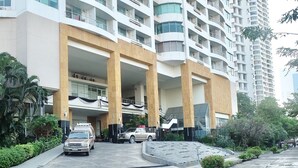 Un hôtel moderne à plusieurs étages, doté d’un atrium central, d’un parking et entouré de verdure.