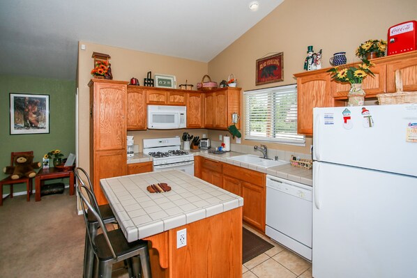A kitchen with wooden cabinets, a white stove, a microwave, and a refrigerator.