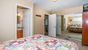 Une chambre à coucher avec un grand lit, un miroir, une armoire et une porte donnant sur une autre pièce.