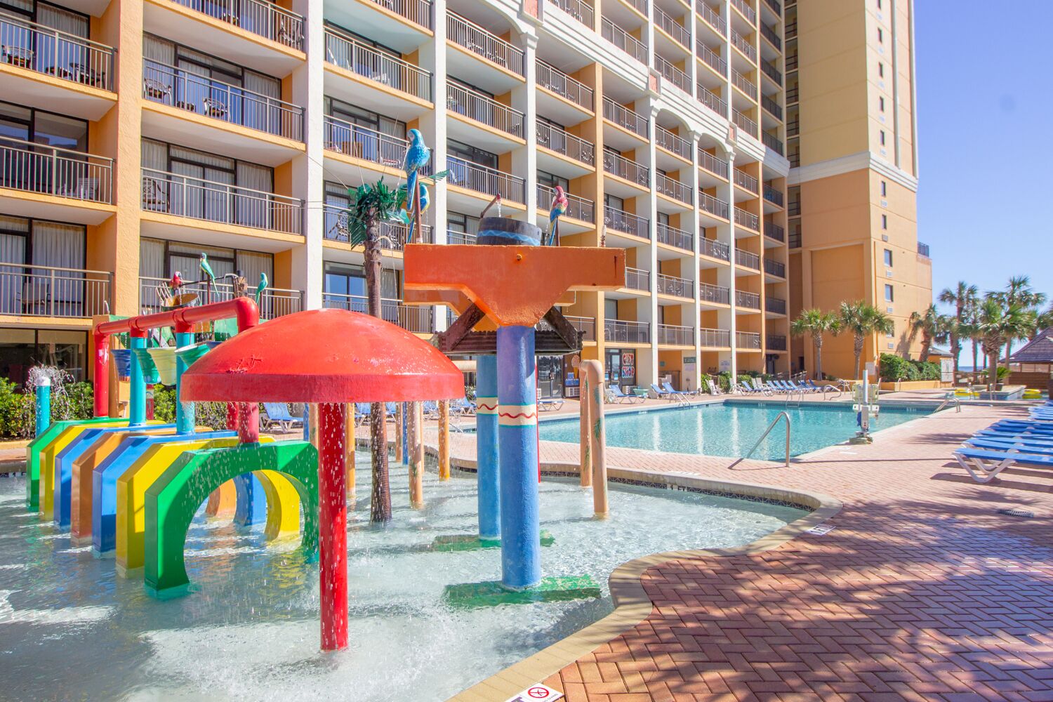 Ein Hotel mit Poolbereich, bunten Wasserspielgeräten und einem großzügigen Gebäude mit Balkonen.