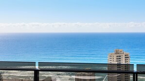 A view of the ocean from a window, with a building in the foreground.