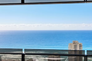 Une vue sur l’océan, prise depuis une fenêtre, avec un bâtiment au premier plan.
