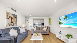 A modern living room with two sofas, a coffee table, and a TV on the wall.