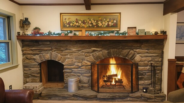 A stone fireplace with a fire, a mantel with various decorations, and a painting above it. - Killington Chalet - Great Space and Location! (Killington)
