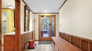 A hallway with wooden paneling, a bench, a red bucket, and a door leading outside. - Killington Chalet - Great Space and Location! (Killington)