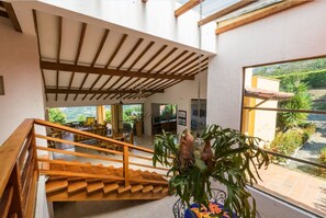 Stunning interior with a grand staircase, high ceiling, and a window offering a garden view.