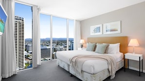 A hotel room with a large bed, two bedside tables, a city view, and a window with curtains. - H Residences Ocean View (Surfers Paradise)