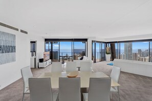 Enjoy a spacious living area with a panoramic city view, central dining table, and comfortable seating area.