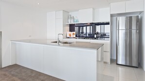 Una cocina moderna con una isla central, electrodomésticos de acero inoxidable y armarios blancos.