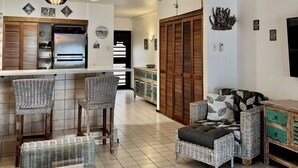 A spacious living area with a kitchen, wicker furniture, and a wooden cabinet. - Spacious Oceanfront Studio Condo A3 at Sand Dollar Condominiums (Kralendijak)