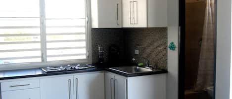 A kitchen with white cabinets, a black countertop, a sink, and a window.