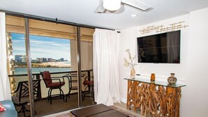 A modern living room with a balcony overlooking a beach and cityscape.