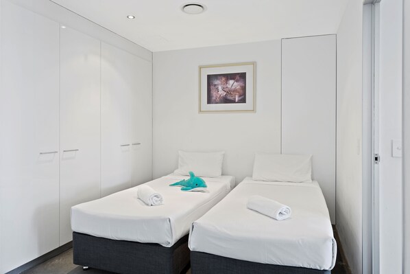 Une chambre d’hôtel avec deux lits simples, une armoire et un tableau encadré au mur.