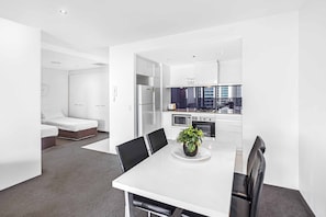 A modern hotel room with a dining area, kitchenette, and a bed. - Circle on Cavill Ocean View (Surfers Paradise)