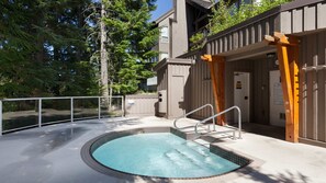 A hot tub area with a pool, wooden deck, and a building with a spa sign. - Popular Ski-in, Ski-out Location, Shared Hot tub (Whistler)