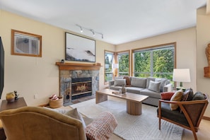 A living room with a fireplace, a sofa, a coffee table, and a large window.