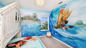 A bedroom with a mural of a beach scene, a wooden bed, and a window with a view.