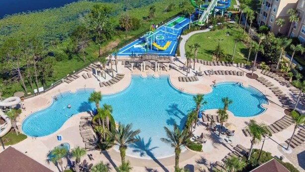 An aerial view of a resort with a large pool, a water park, and a beach area.