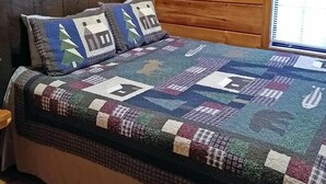 A wooden cabin room with a bed, a headboard, and a window with curtains. - Bear Cabin - 2 Bedroom/1 Bath Vacation Rental (Franklin)