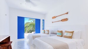A hotel room with two beds, a desk, and a view of palm trees through a blue door. - Luxury Ocean Front Villa,  6BR (12 pax) Breakfast includes + infinity pool (Isla Mujeres)