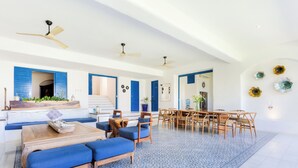 A spacious living area with a wooden coffee table, blue cushioned seating, a dining table with chairs, and a patterned blue rug. - Luxury Ocean Front Villa,  6BR (12 pax) Breakfast includes + infinity pool (Isla Mujeres)